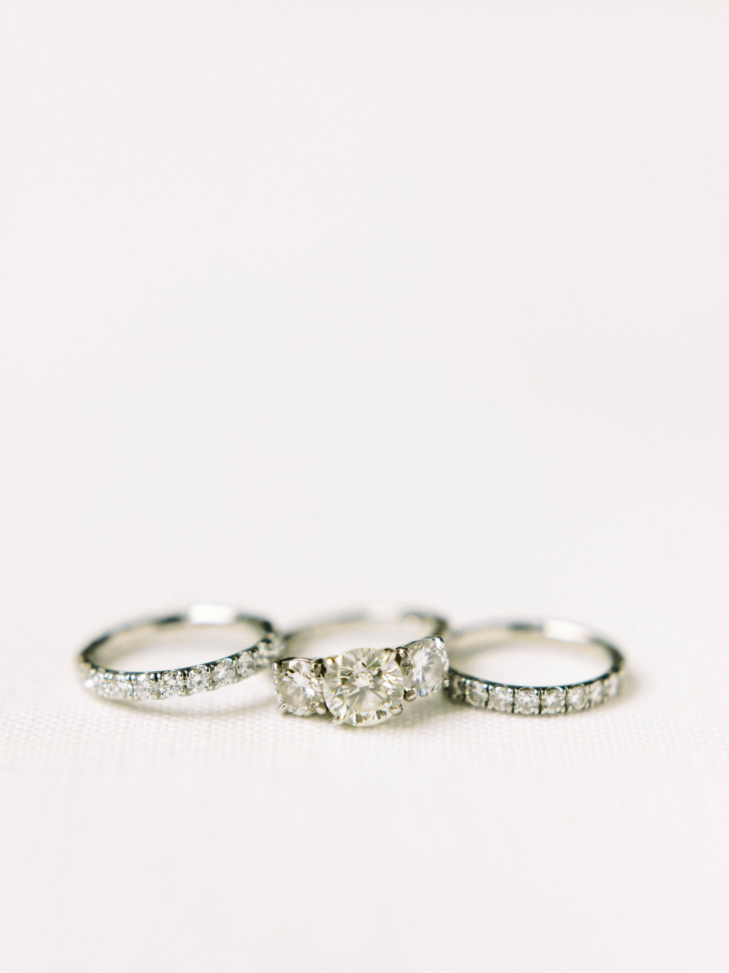 Three silver rings with diamonds, one with a large heart-shaped diamond, set against a white background.
