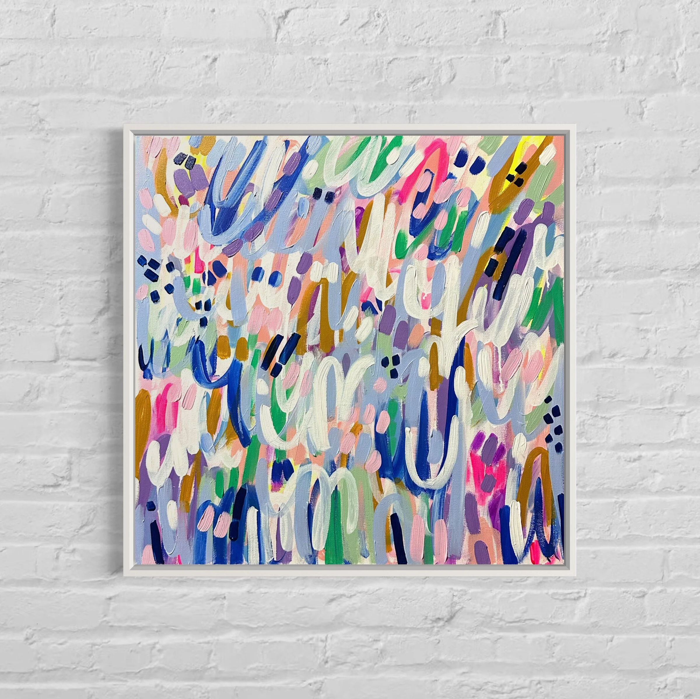 Abstract colorful painting with bold brushstrokes in various colors including pink, purple, blue, green, brown, white, orange, and yellow, framed and hung on a white brick wall.