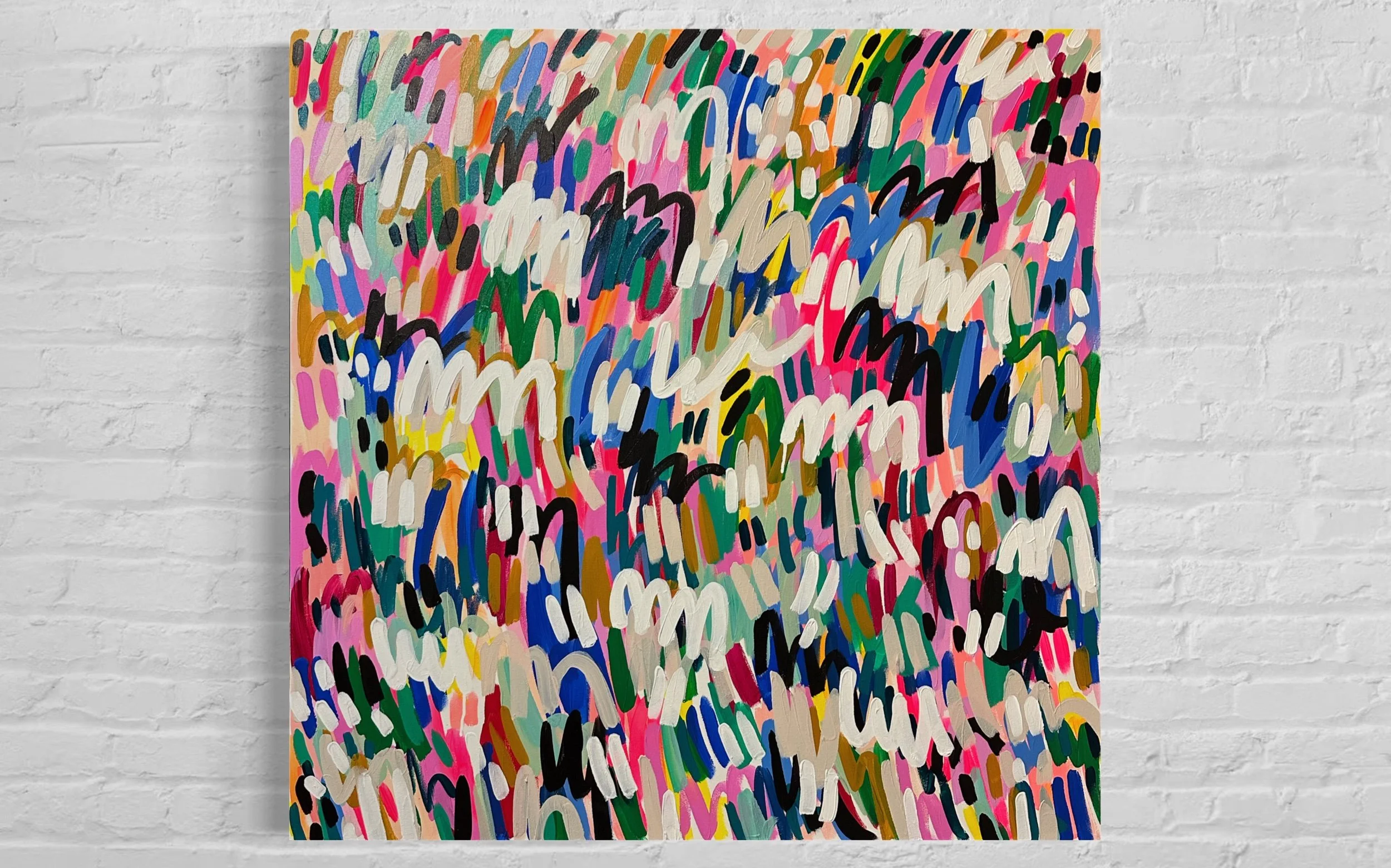 Abstract artwork with vibrant, multicolored brushstrokes on a canvas mounted on a white brick wall.
