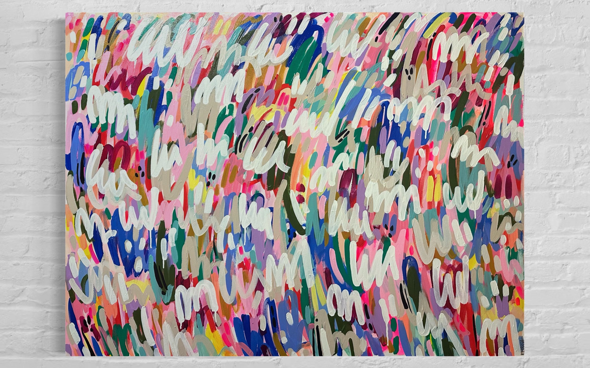 Abstract colorful painting with dynamic, overlapping brushstrokes in pink, blue, white, green, black, and yellow hues on a canvas, mounted on a white brick wall.