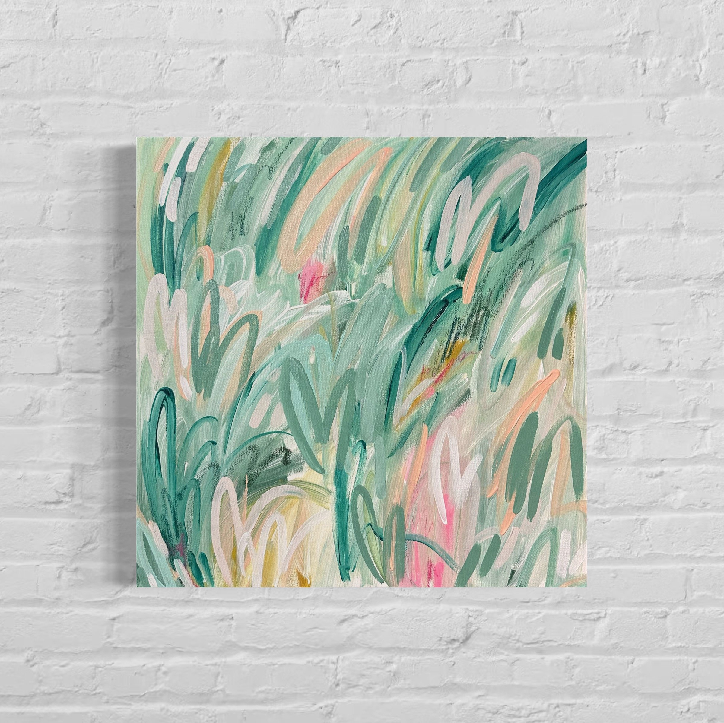 Close-up of an abstract painting with colorful brushstrokes in green, pink, yellow, and white, mounted on a white brick wall.