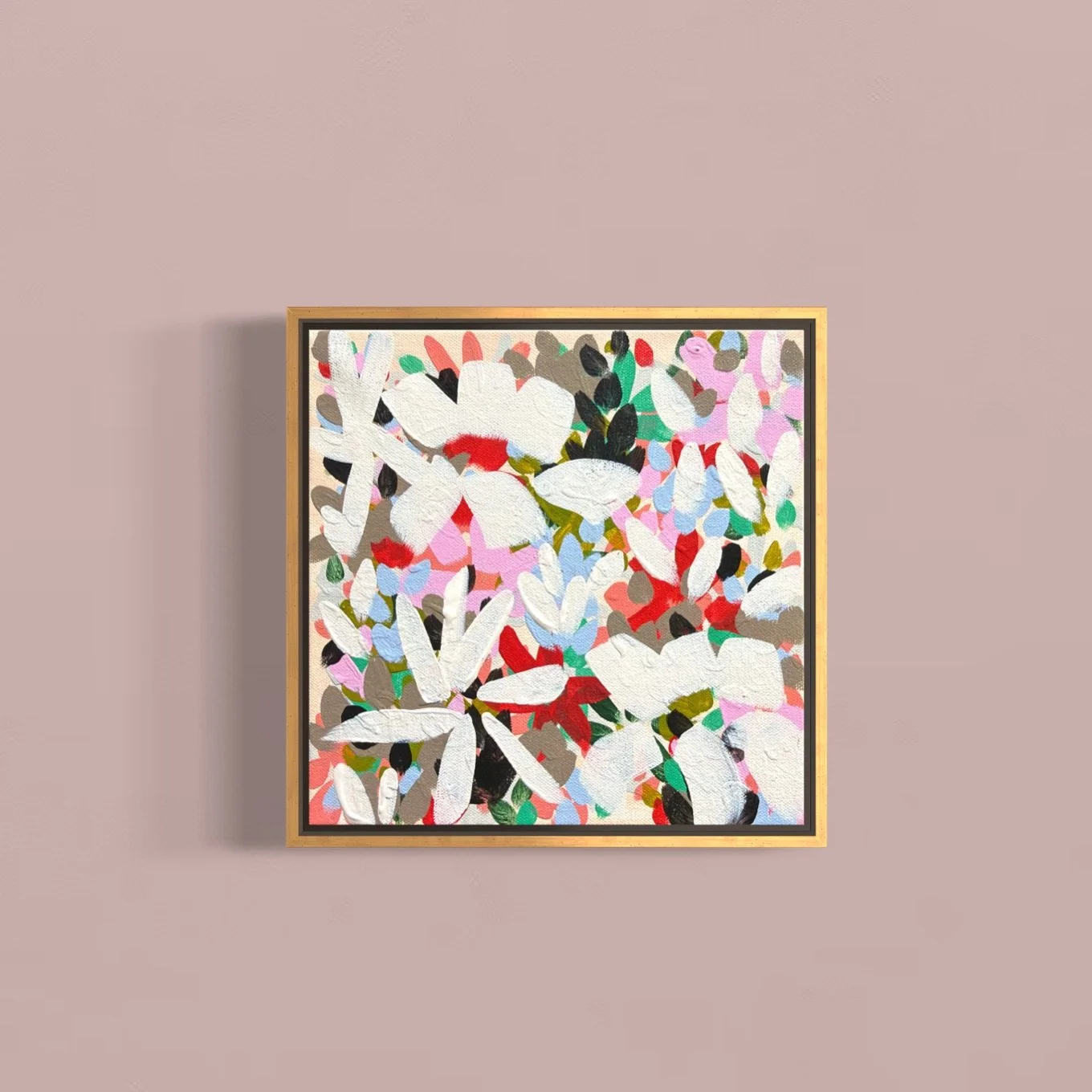 Abstract floral painting with white, red, pink, green, black, and blue colors in a gold frame, hanging on a pink wall.