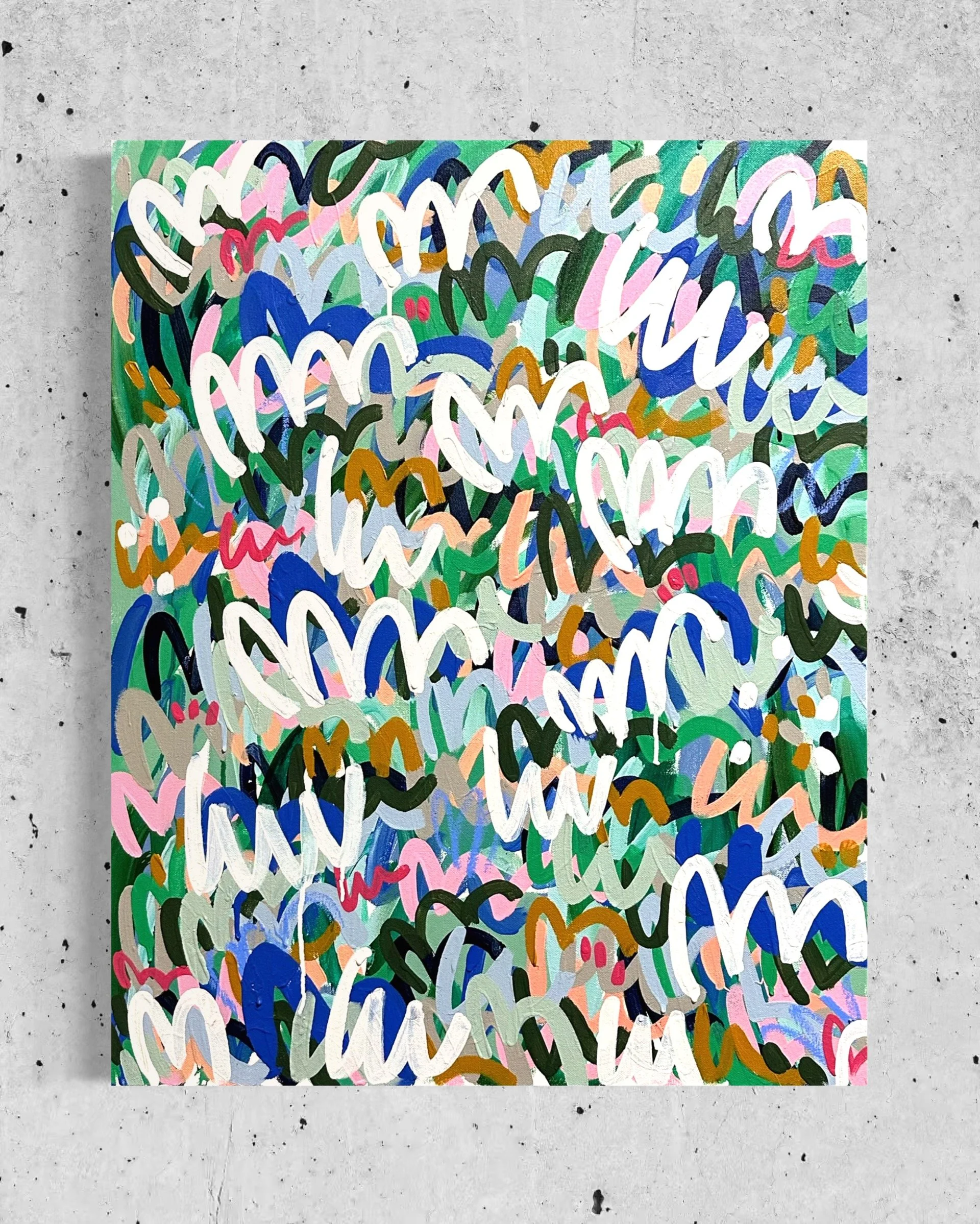 Abstract colorful painting with swirling lines and brushstrokes of pink, blue, green, black, white, and gold, on a gray concrete background.
