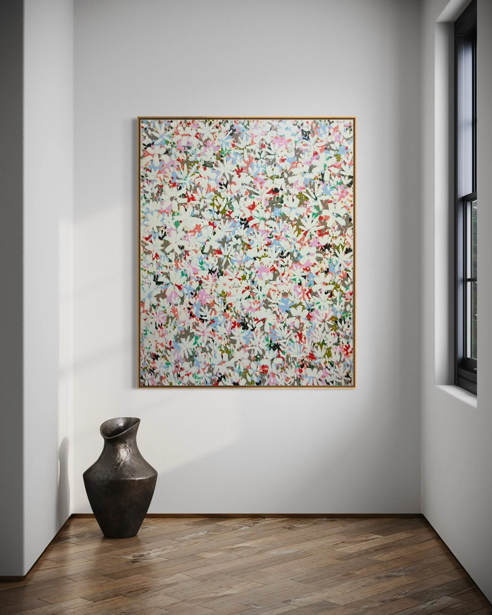 An abstract floral painting on a white gallery wall with a dark ceramic vase on the wooden floor beside a window.