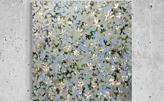 Abstract mosaic artwork with small, irregular shapes in shades of gray, blue, beige, and black, mounted on a concrete wall.