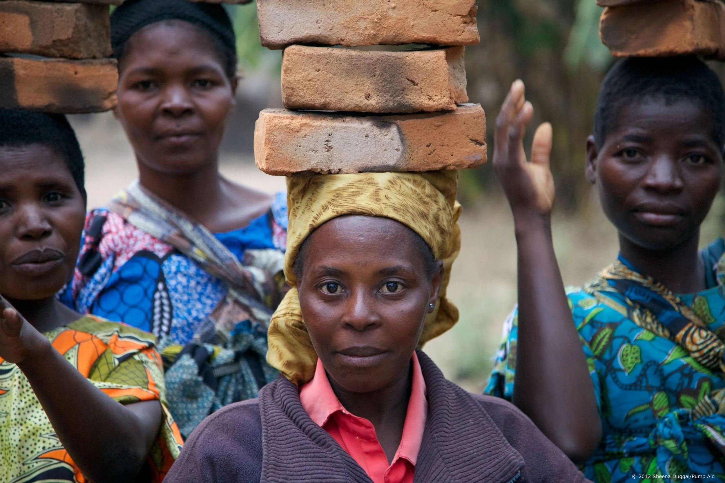 Brick Ladies Malawi 2012 Women carrying bricks for lining a muddy water well.