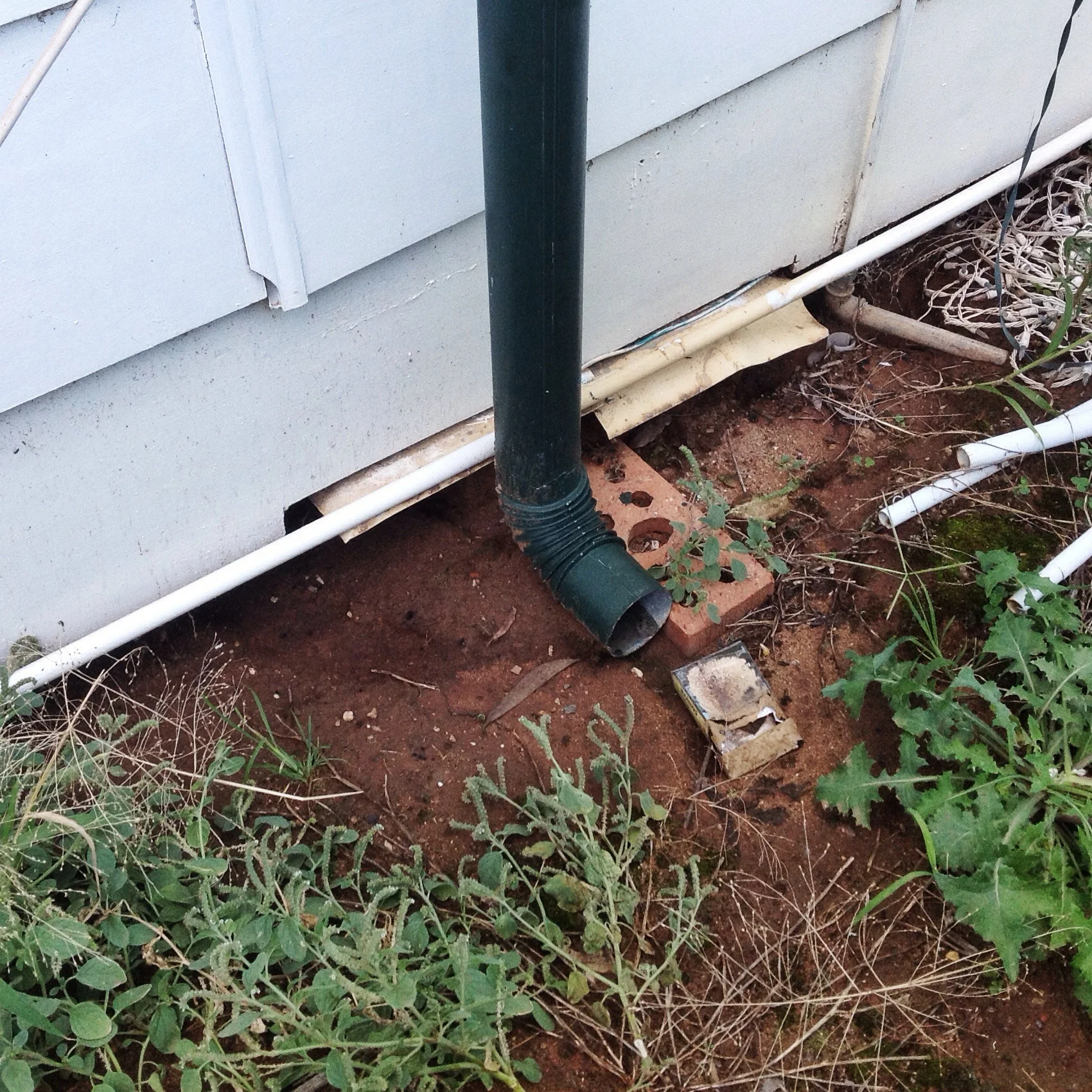 A downpipe draining against a building, it's like a pub with free beer for termites!