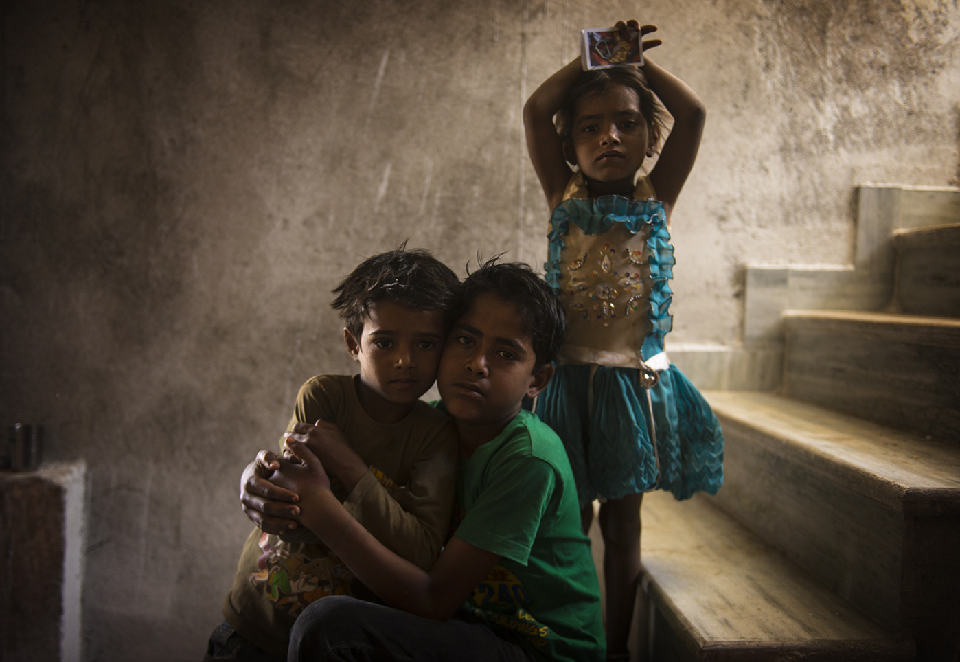 Three children pose inside their home in Udaipur.