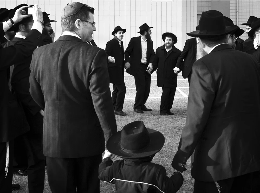 Once a Jewish wedding reaches its close, the wedding party erupts in shouts of “Mazel tov!” meaning “good luck.” Friends and family pull the bride and groom into tight embraces and the men begin to join hands and dance in a circle to give joy to the bride and groom.