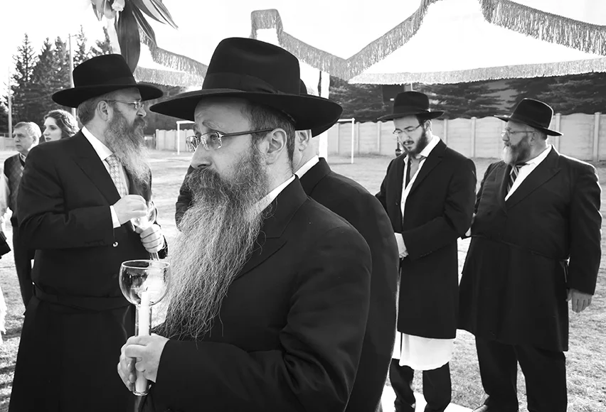 Standing beneath the traditional wedding chuppah , Rabbi Menachen Matusof holds a candle as he watches his veiled daughter walk down the aisle toward him. To behind his is the father of the groom, Rabbi Yoseph Rosenblum (left), the groom Mendel Rosenblum (centre) and Rabbi Laine (right), the grandfather of the bride. The groom is dressed in a Kitl (literally meaning “little coat”), a sacred article of clothing to symbolize the holiness of his wedding day.