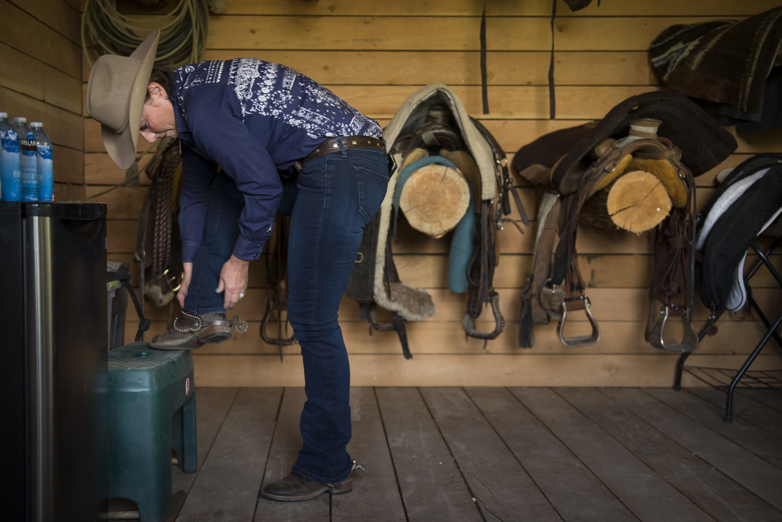 Laura Laing readies her spurs before heading out to wrangle a pair of horses to move cattle through the ranch.