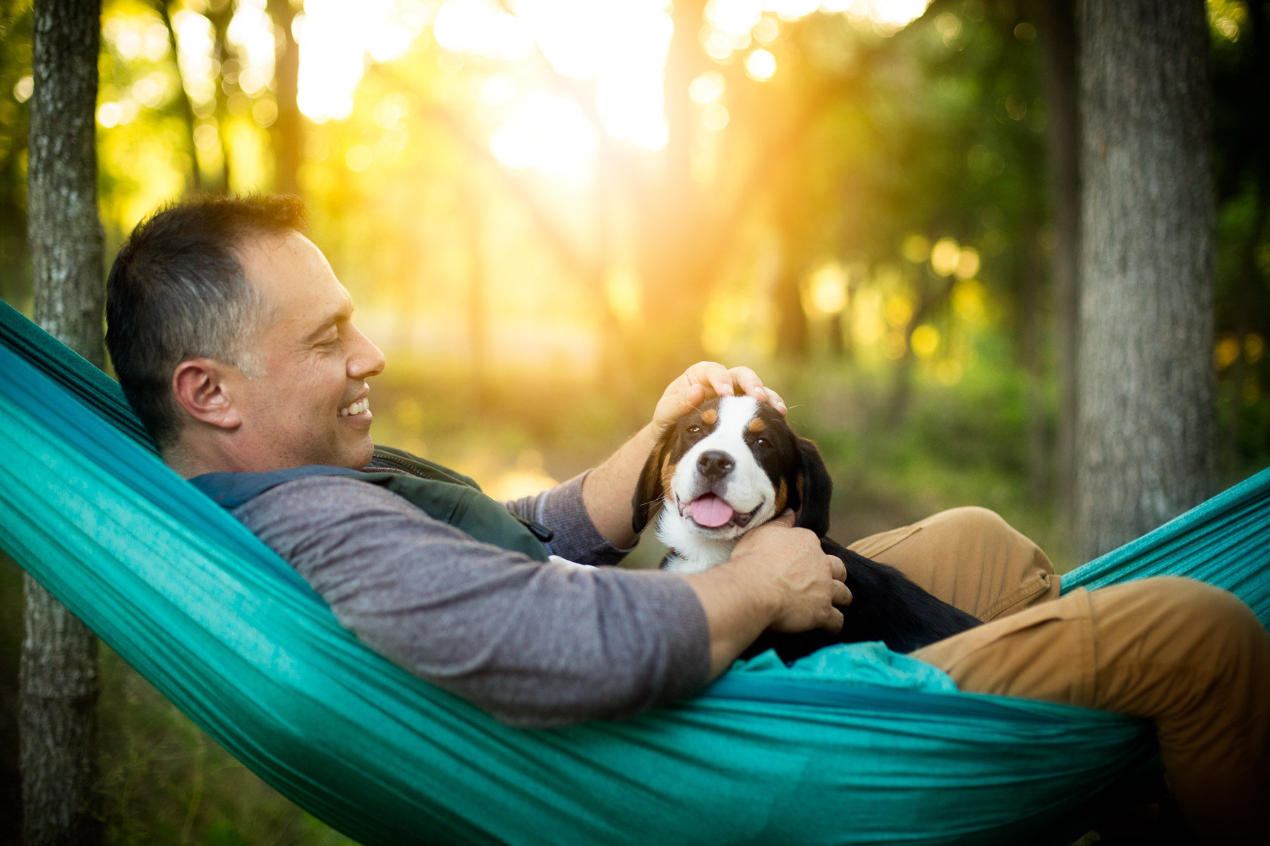 man-with-dog-puppy-on-hammock-camping-dog-photography.jpg