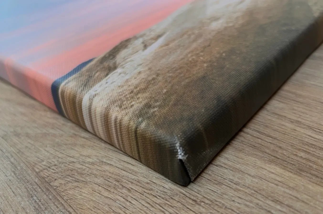 Close-up of the stretched edge and corner of a CanvasDiscount canvas print showing the wrapped image continuing onto the sides, with a minor ink scuff visible at the corner