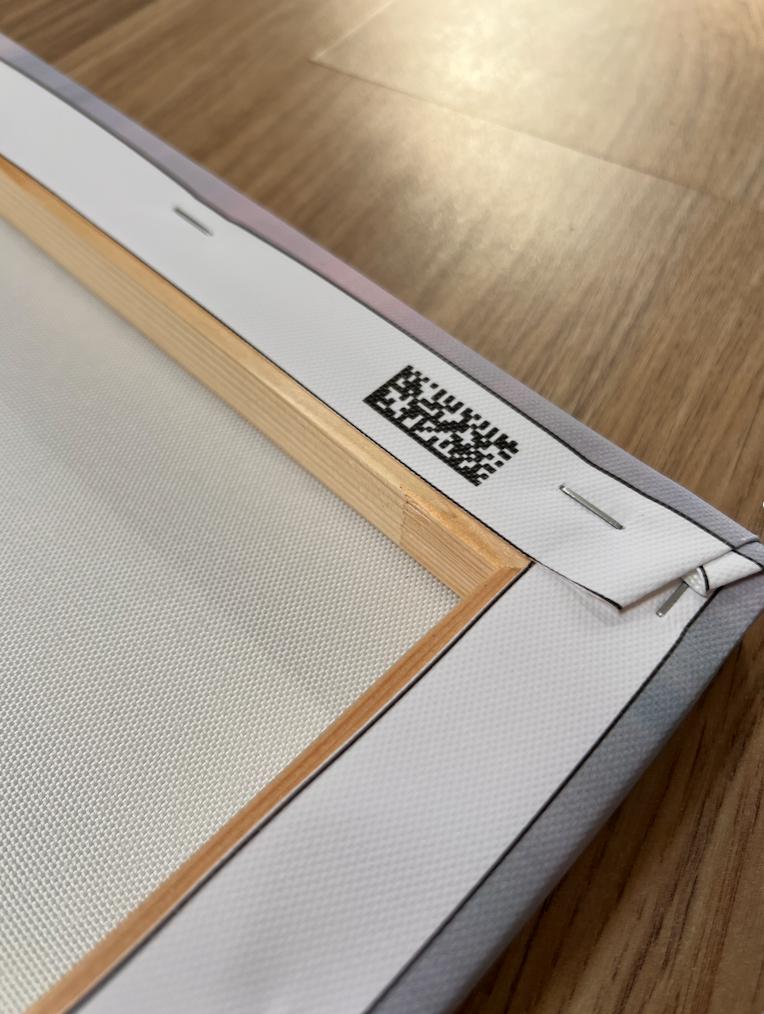 Back of a CanvasDiscount canvas print showing the wooden stretcher frame, stapled canvas edges, and a QR code label, revealing the solid build quality and construction
