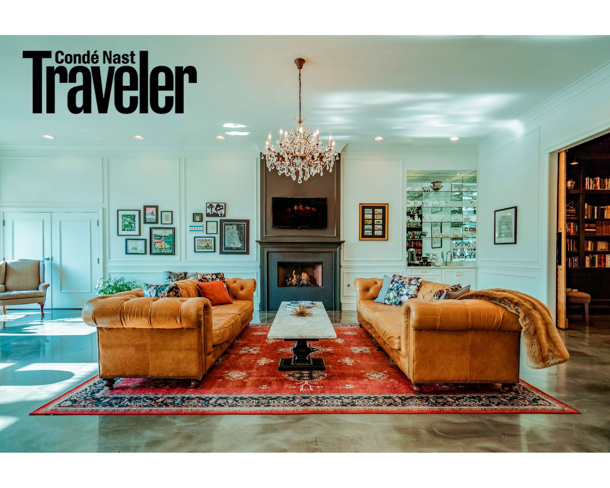 Club Room with crystal chandelier above marble coffee table between two leather couches. All in front of a fireplace.
