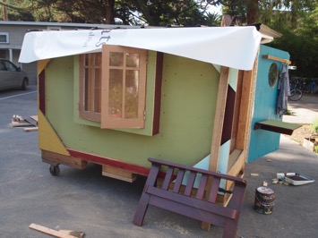 Pictured: House #1, wooden crate on wheels turned into a colorful home complete with pot-lid windows, roofing, a door, and trimming.