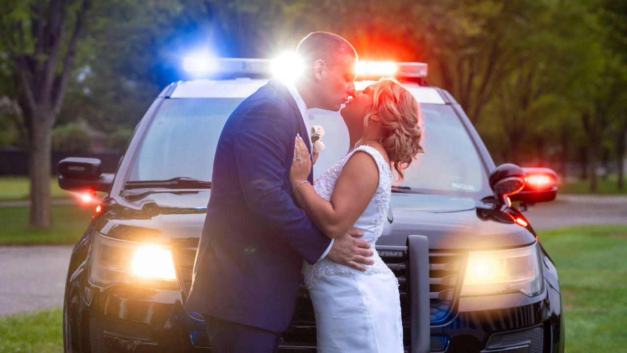 A smiling couple in wedding attire hugging outdoors at sunset in a park captured by a wedding photographer in Michigan.