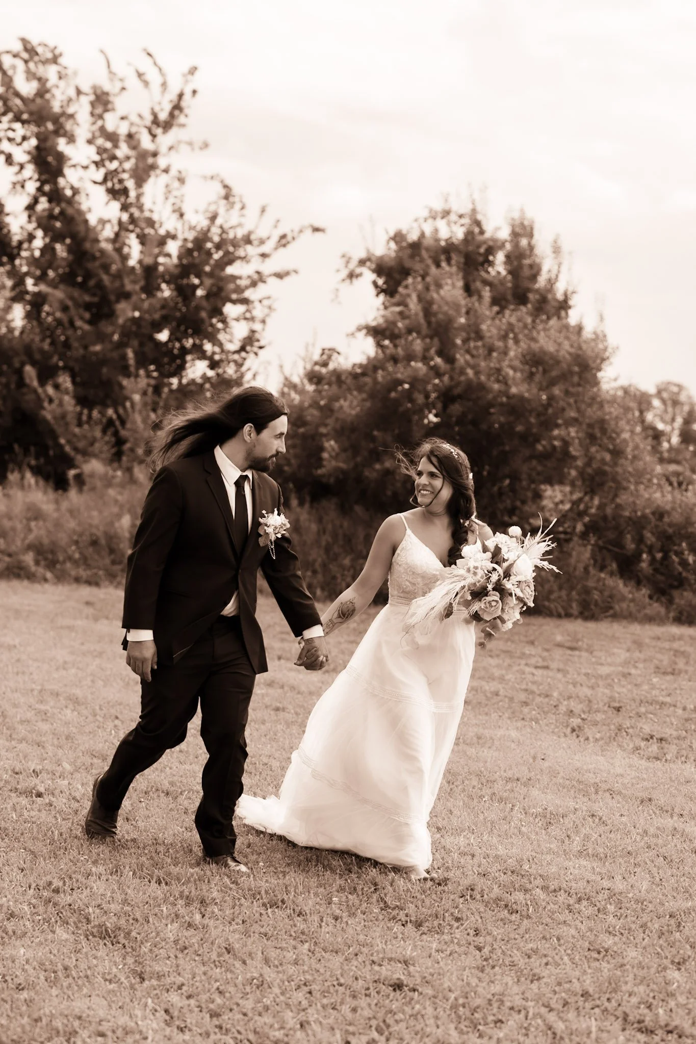 Bride and groom holding hands, walking past the bridal party as they hold up lightsabers during their wedding In Ann Arbor area.