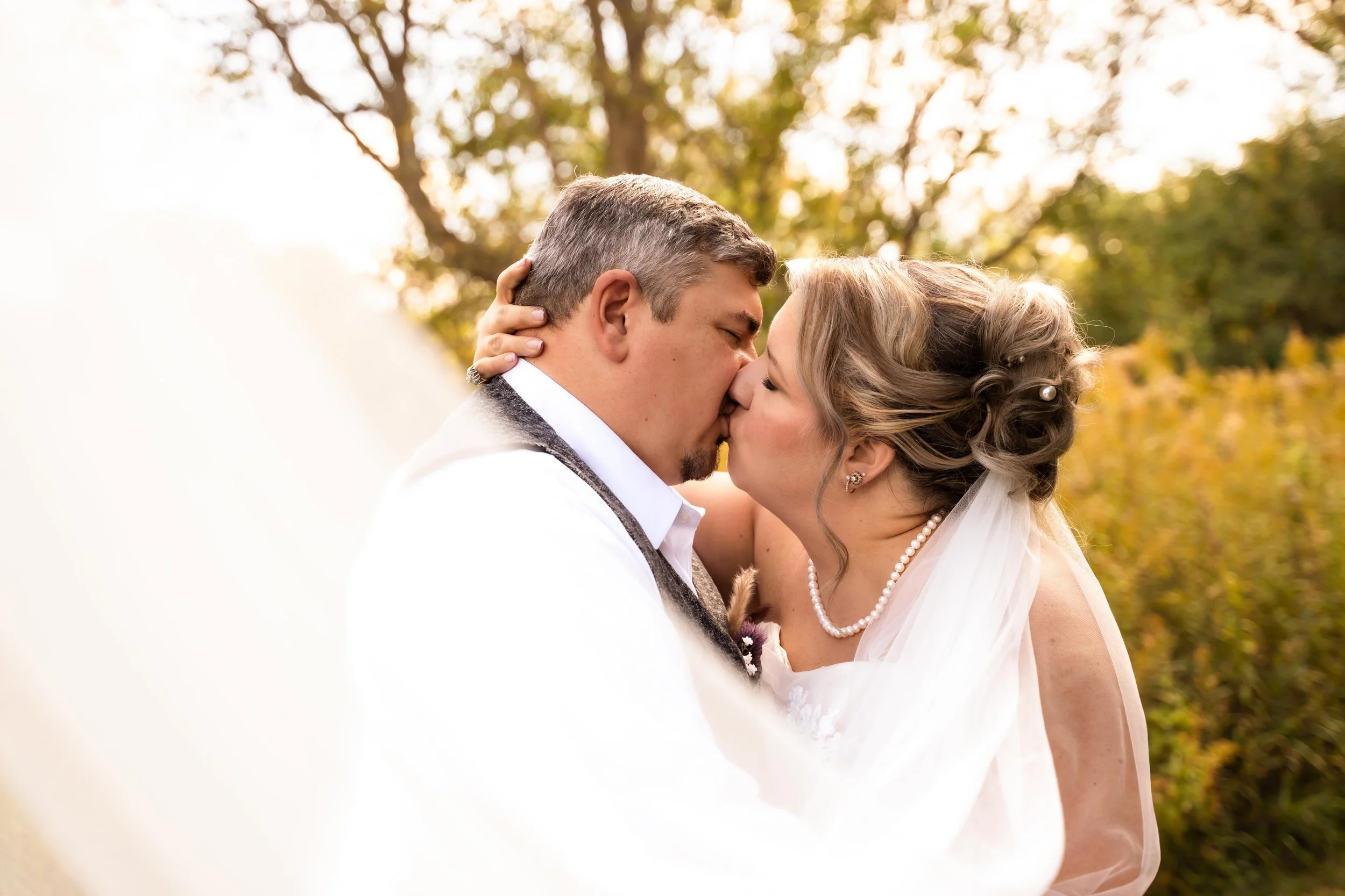 Bride and groom kissing and embracing in the sun.