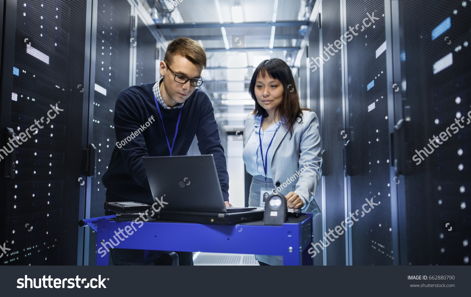 stock-photo-caucasian-male-and-asian-female-it-technicians-working-with-computer-crash-cart-in-big-data-center-662880790.jpg