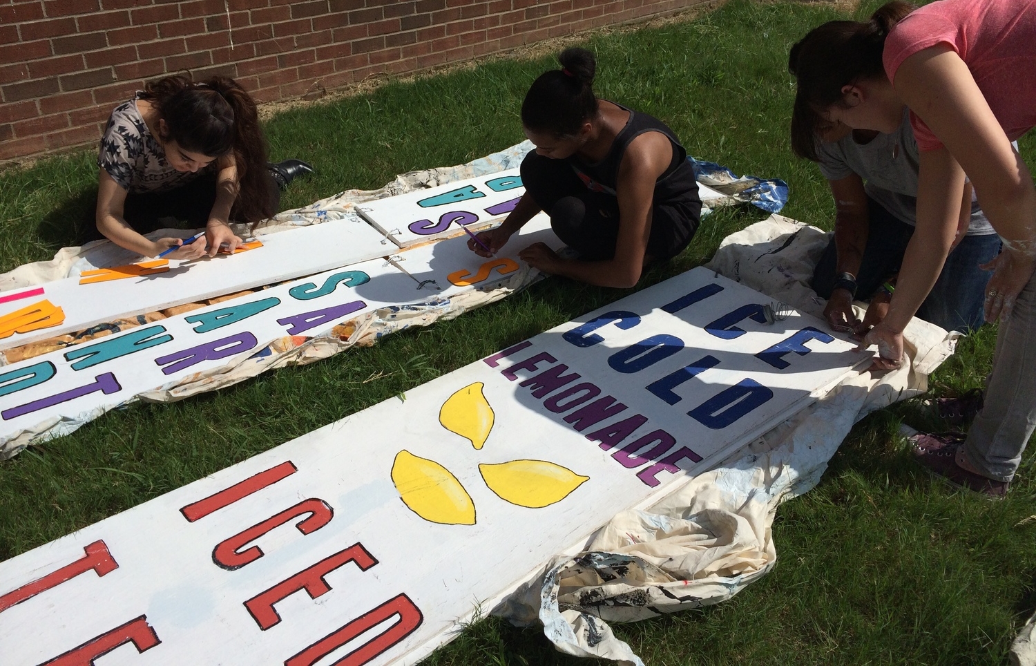 These Germantown High School students are putting the finishing touches on signs for the Poplar Pike Playhouse's various areas at the Germantown Festival.