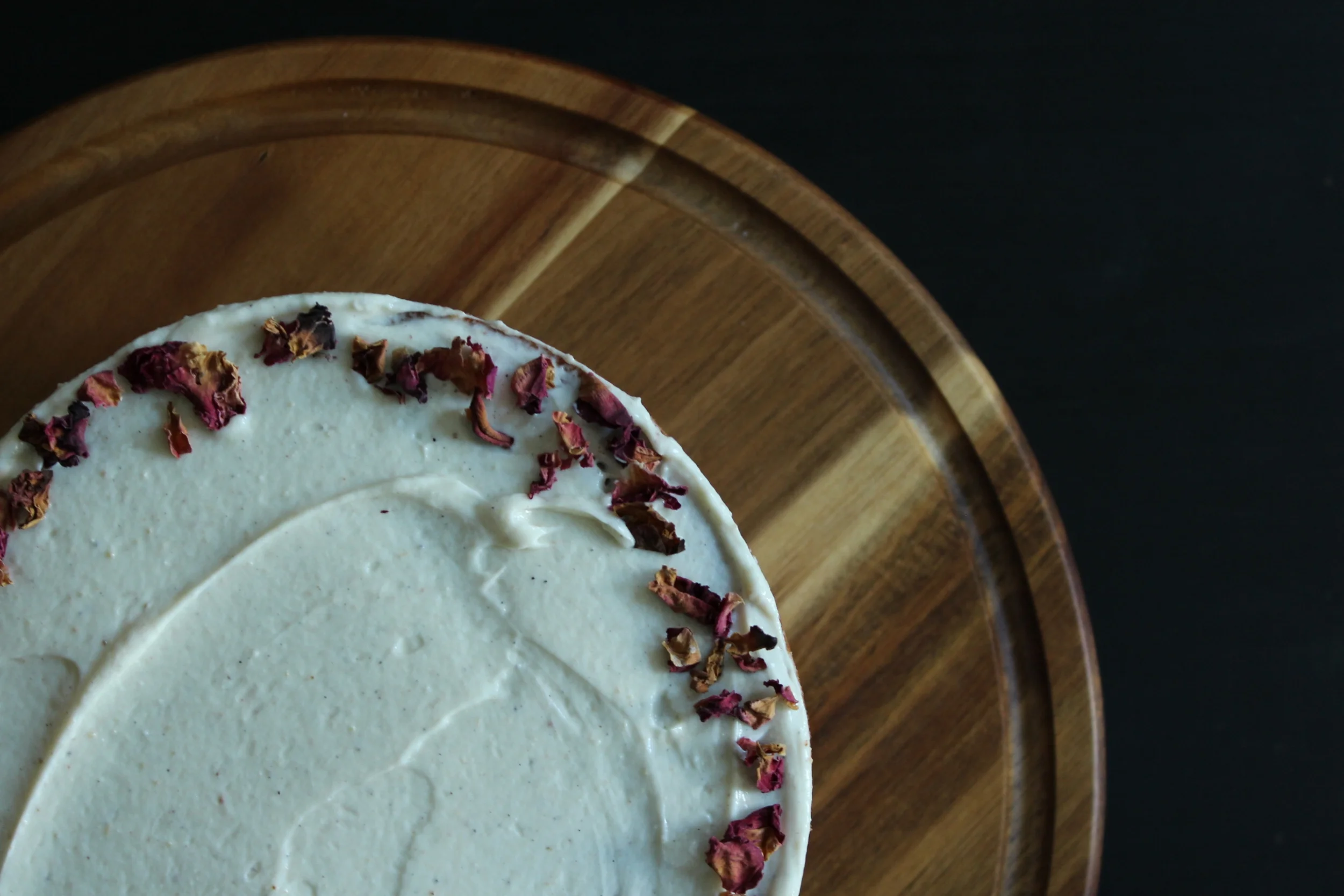 overhead view of tahini honey cake, cardamom goat cheese frosting, rose petals