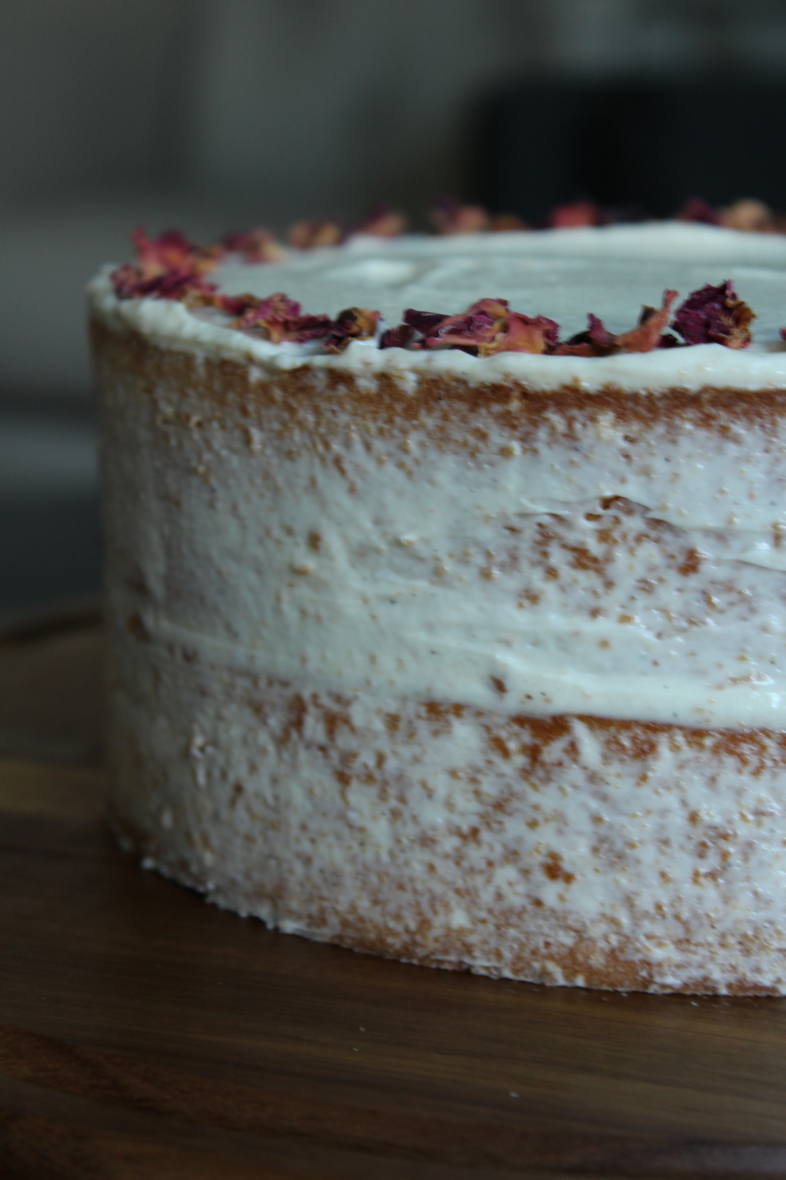 side view: tahini honey cake, cardamom goat cheese frosting, rose petals