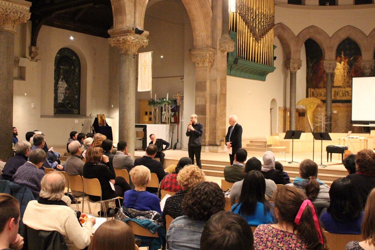Hanna Khoury translating Tom Lloyd's summary of the Chamber Singers Berlin tour into Arabic for the Syrian refugees in attendance.