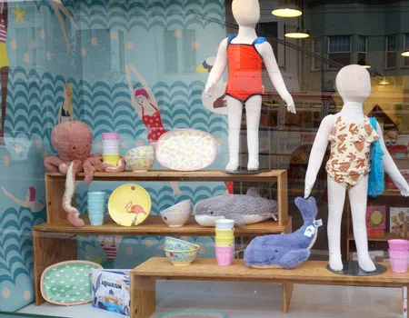 Swim themed window display featuring aquatic stuffed animals, summer fruit dishware and kid's swimwear. Spring/Summer 2018.