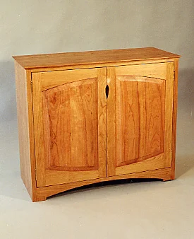 handmade hardwood two door cherry buffet with sculpted pulls and arched frame and panel doors