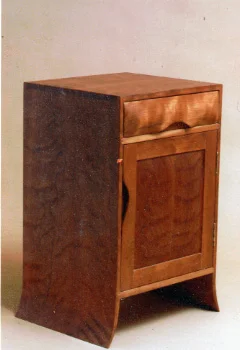 handmade hardwood cherry dovetail side cabinet with curved side panels, frame and panel door, and sculpted integral pulls