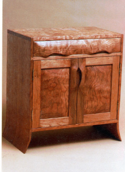 handmade hardwood dovetail side cabinet with curved side panels, frame and panel door, and sculpted integral pulls