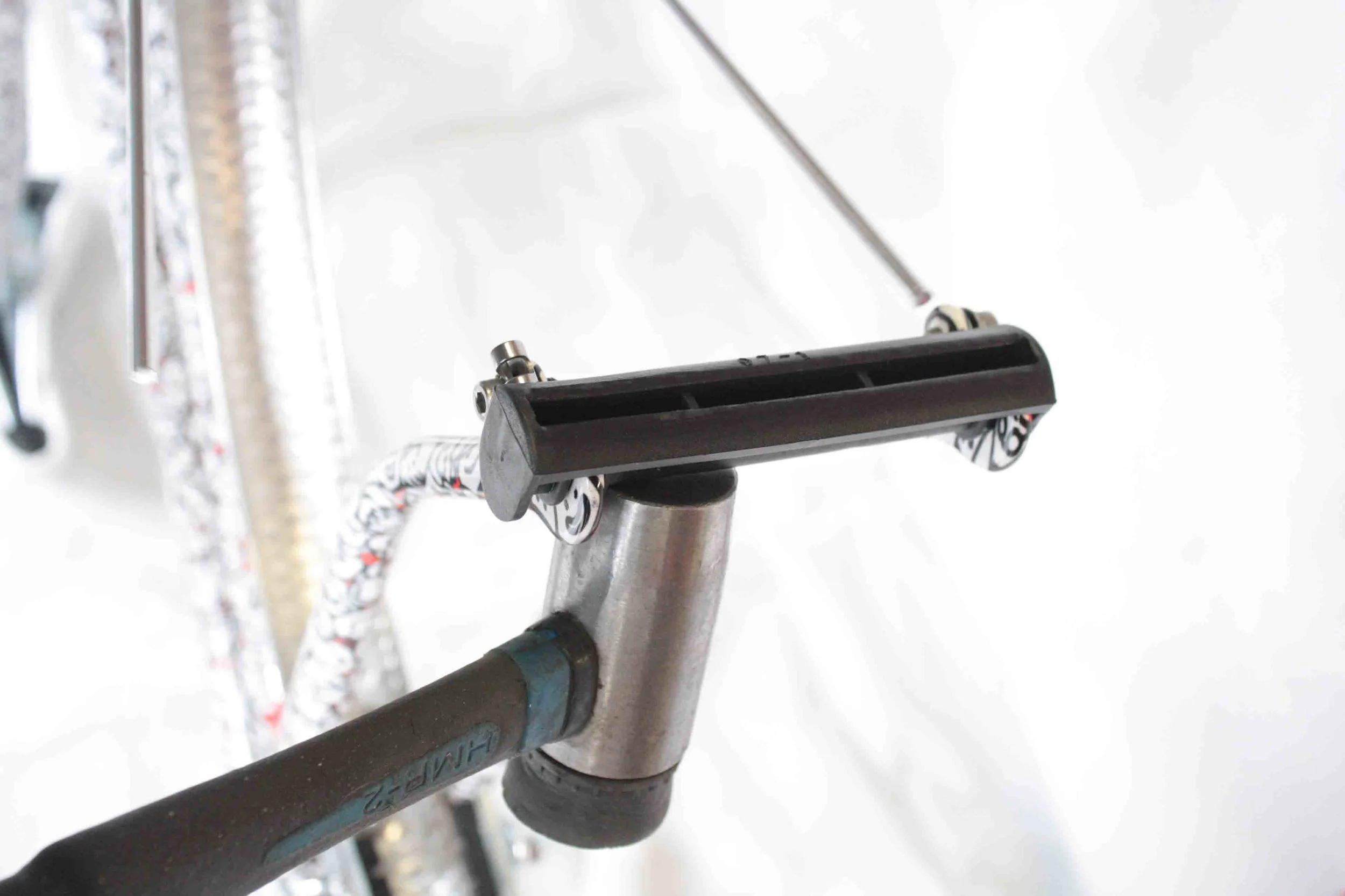Flip the bike upside down so that it is resting on the saddle and handlebar grips. Remove the plastic cover from the front fork. If it is tight, use a hammer to knock it out.