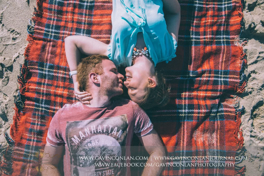 creative portrait of Victoria and James laying down on their blanket whilst looking at each other on the beach near Boscombe Pier . Engagement Session in Bournemouth, Dorset by gavin conlan photography Ltd