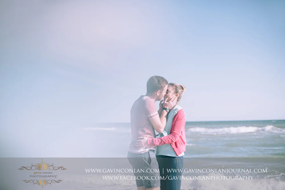 Victoria and James sharing a kiss on the beach near Boscombe Pier . Engagement Session in Bournemouth, Dorset by gavin conlan photography Ltd