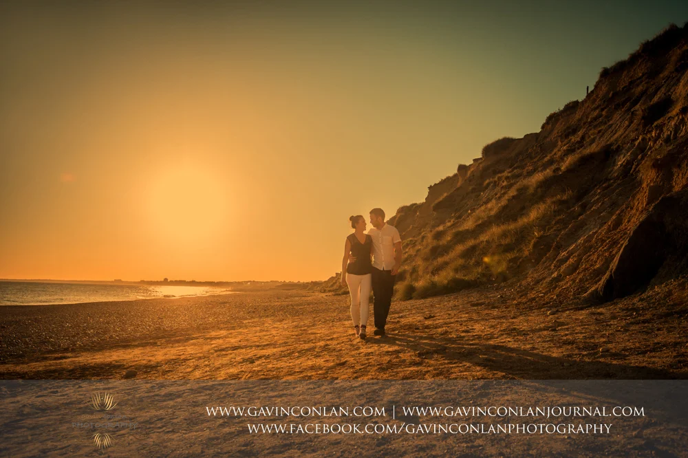 creative portrait of Victoria and James walking along the beach at Hengistbury Head at sunset. Engagement Session in Bournemouth, Dorset by gavin conlan photography Ltd