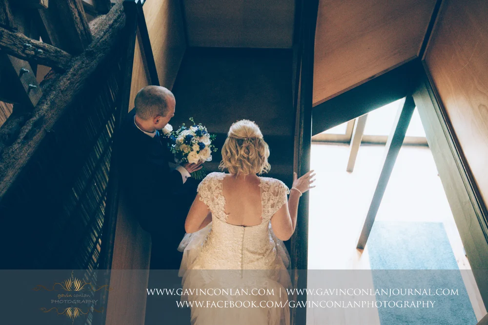 creative portrait of the bride and her brother walking up the stairs to the wedding ceremony. Wedding photography at The Barn Brasserie by Essex wedding photographer gavin conlan photography Ltd