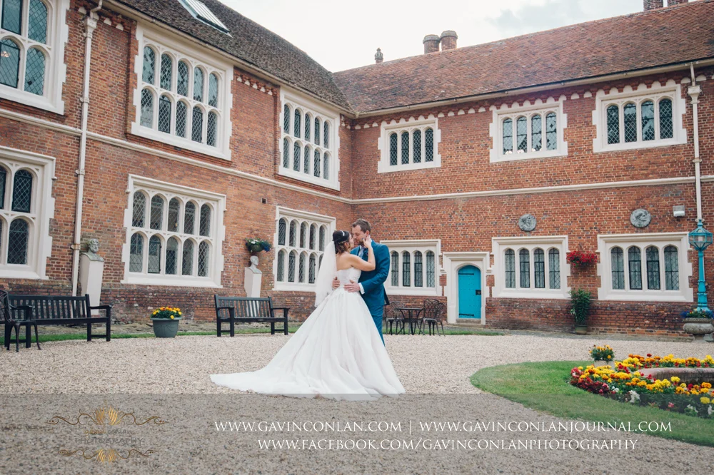 creative portrait of the bride and groom sharing a kiss in the inner courtyard of Gosfield Hall. Wedding photography at Gosfield Hall by Essex wedding photographer gavin conlan photography Ltd