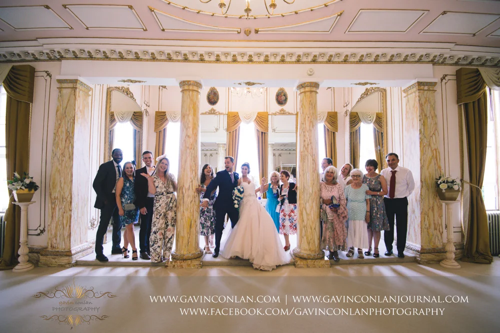 fun portrait of the bride and groom with some of their guest in The Rococco Suite during their tour of the stunning rooms. Wedding photography at Gosfield Hall by Essex wedding photographer gavin conlan photography Ltd