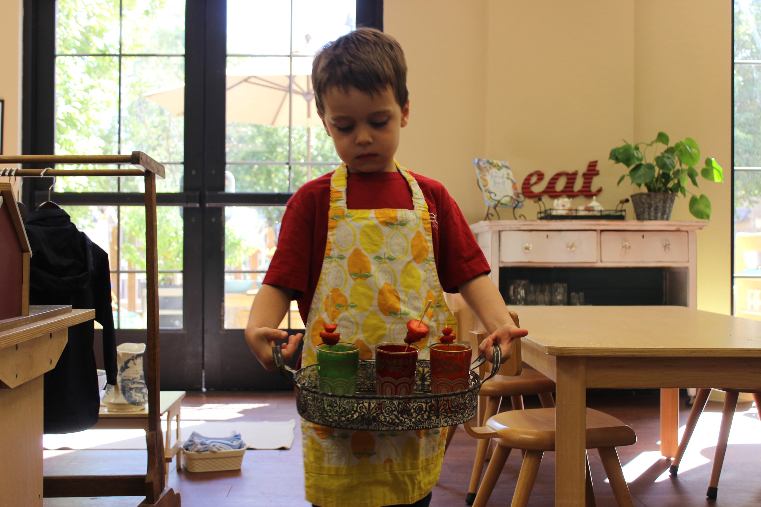 Carrying his fresh squeezed lemonade garnished with strawberries to serve to the office staff. 