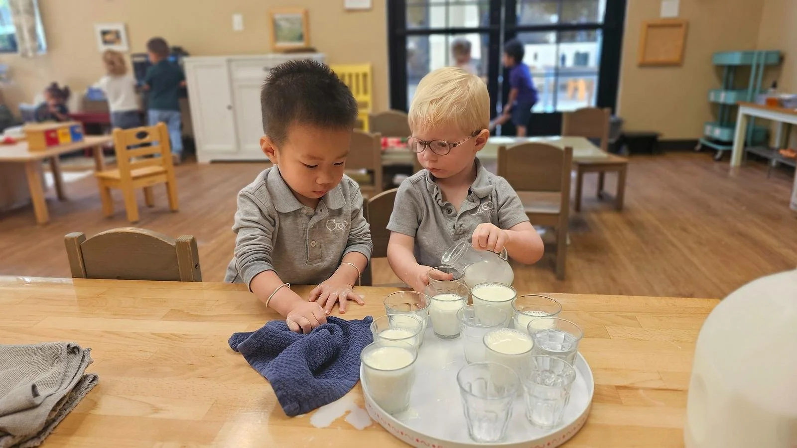 Alvin wiping up a spill and callum pouring milk.jpg