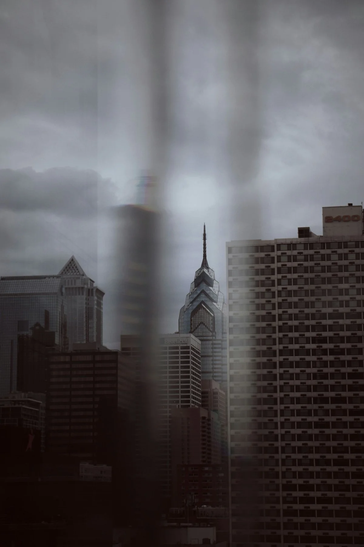 New  York City skyline on a cloudy day with tall modern buildings, including a distinctive spire, and heavy overcast skies.