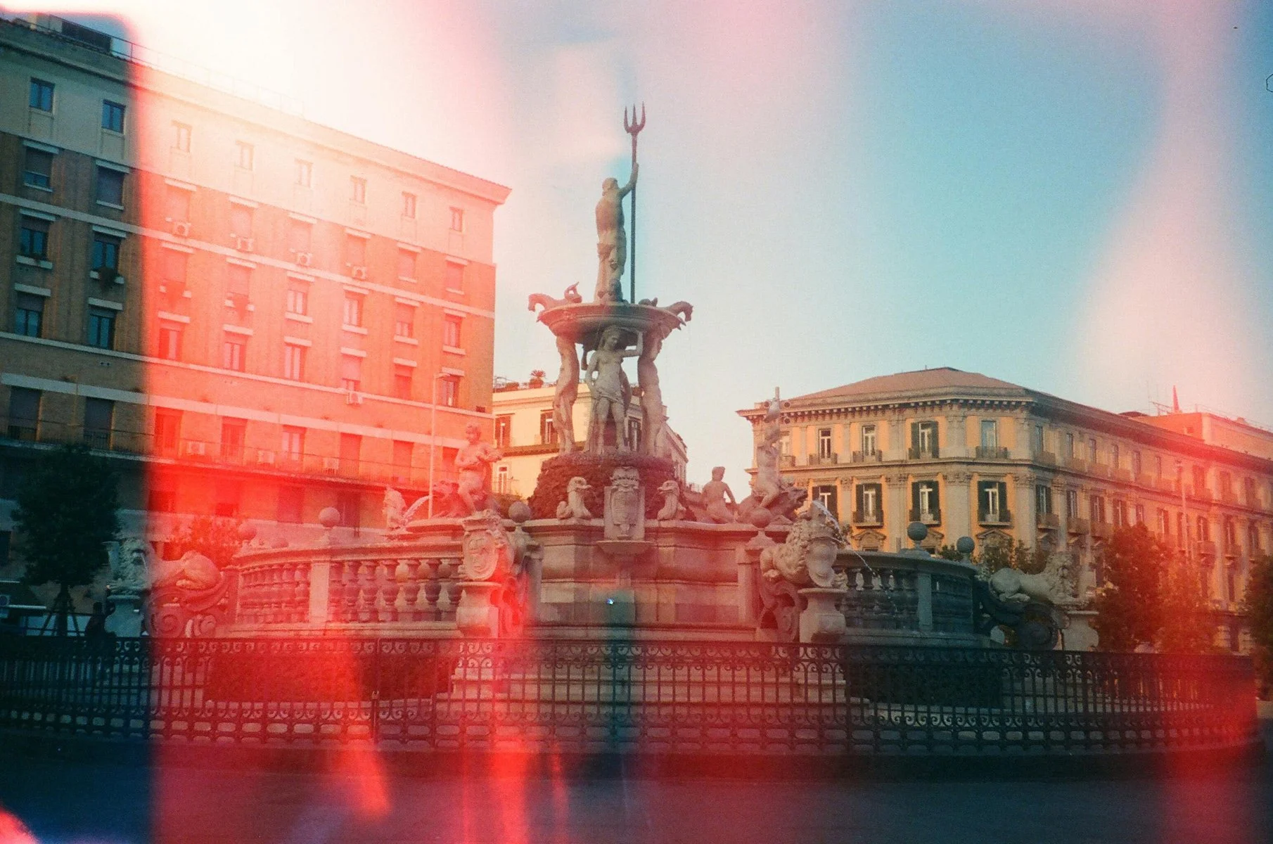 Historical fountain with statues of mythological figures and a central figure holding a trident in an Italian city square, surrounded by ornate buildings.