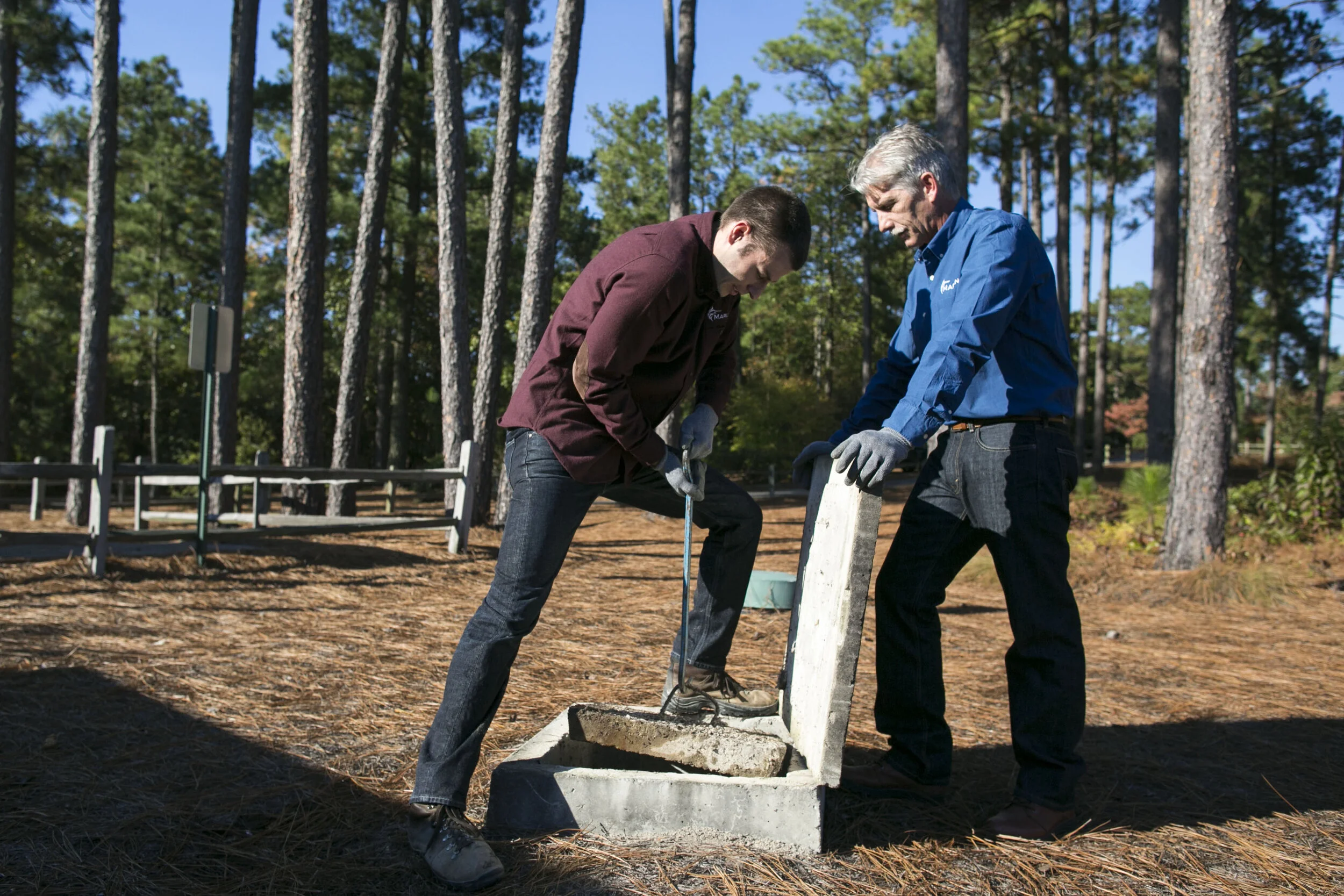  Field Service Manager Brad Redden, left, and Owner Jeff Kerr, right, remove the lid of a septic tank cover during an inspection of a commercial site in Seven Lakes, North Carolina. 