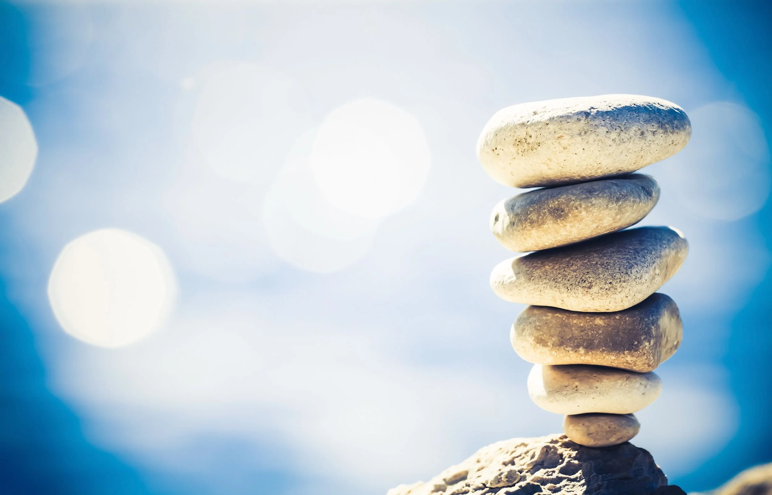 Inverted rock cairn with small stone at bottom supporting larger stones above, symbolizing Big Tech title compression where modest titles support significant scope