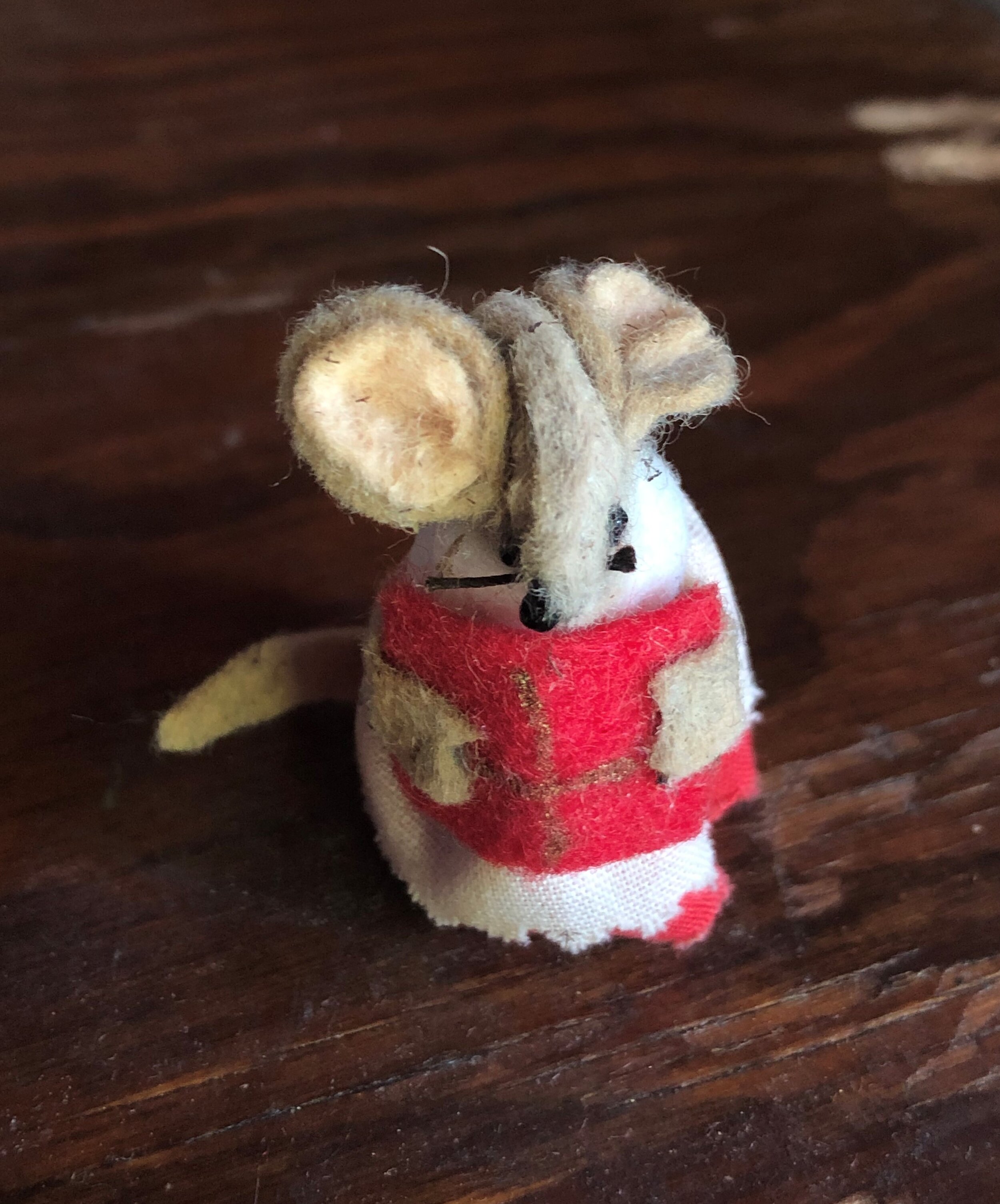 Small felt mouse holding a red book with a gold cross