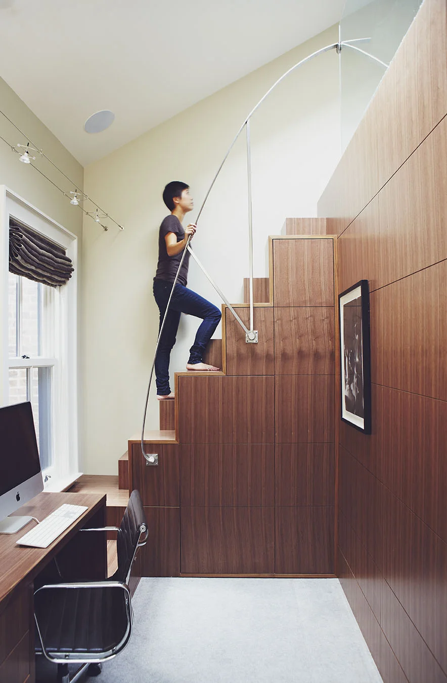 As a 2,200 sq.ft. rowhouse sandwiched between two properties, it was necessary to get creative in designing the most functional space possible. A small, narrow space was converted into a study with a loft for guests. A steep incline to the loft required a clever solution. Staggered blocks and a parabolic railing shape lend to the style, but also to the comfort and safety. Walnut panelled walls and stairs not only house laundry facilities but a ton of hidden storage.