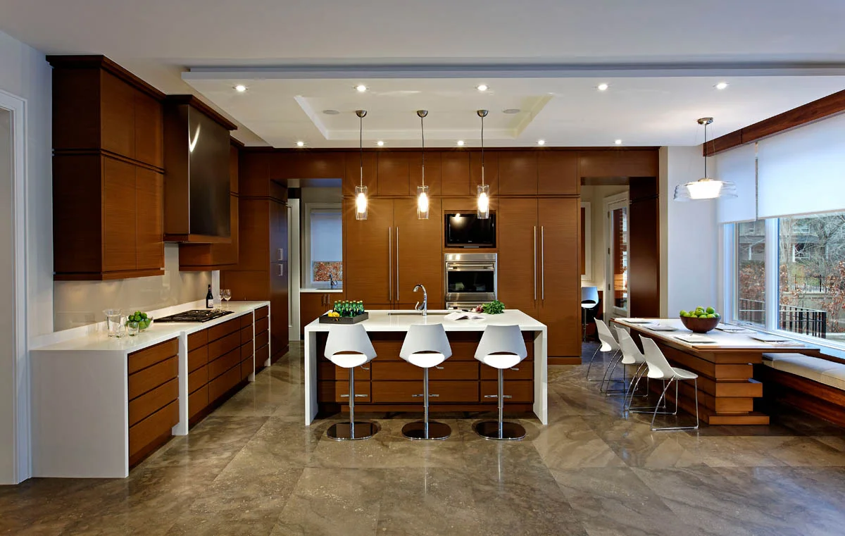 In this pared down, yet welcoming space, the limestone flooring pattern is made even more prominent by the contrast with the simplicity of the kitchen cabinetry. The ceiling detail, “stacked and wrapped” counter units and breakfast table reflect the layering and sculpting throughout the home.