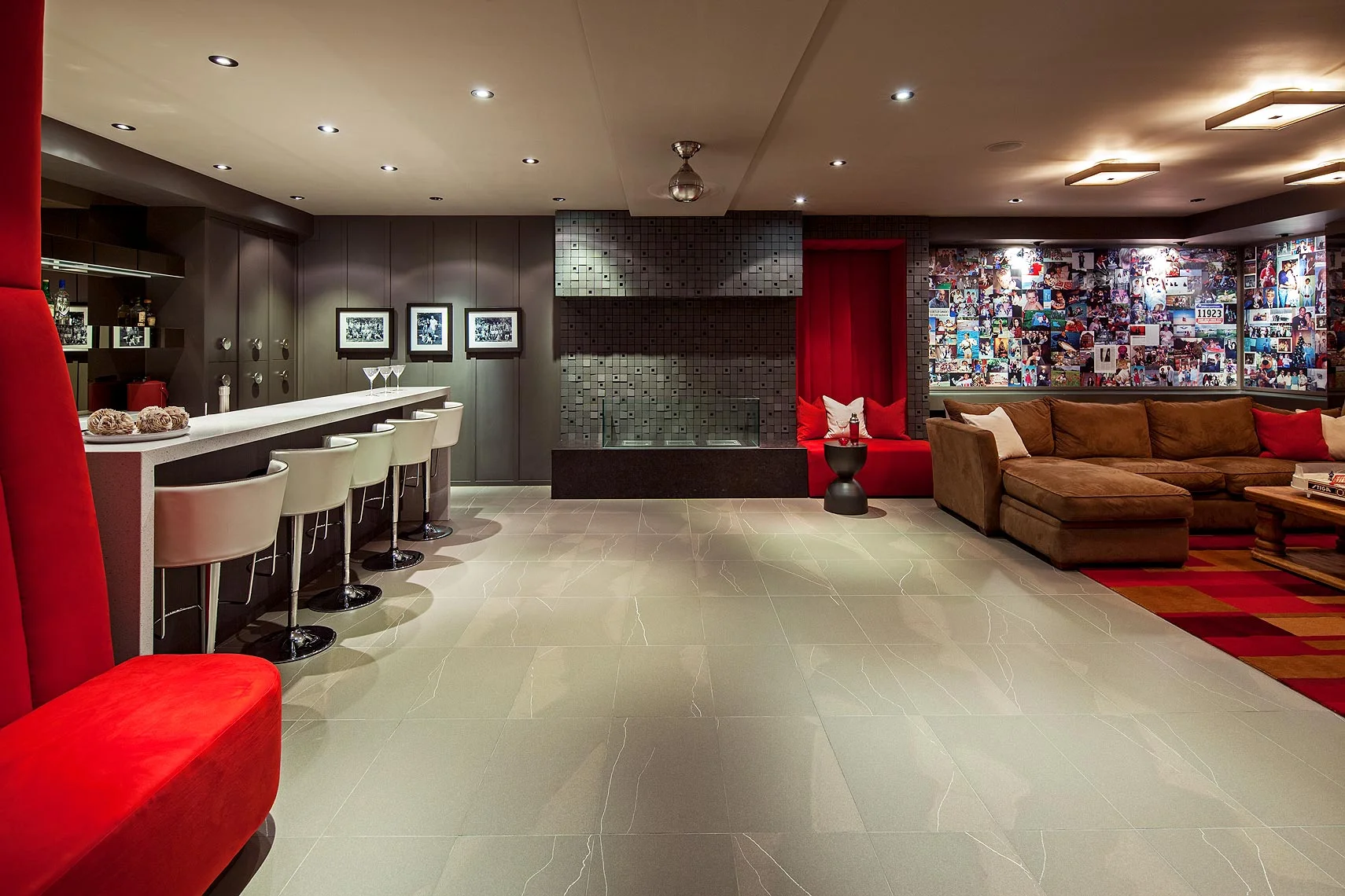 This lower level relaxation space is much used by the family of four and their friends, whose lives are documented in the colourful collage of photos that is an important element of the décor. Simple, comfortable furnishings are set against a contemporary board and batten wall treatment. Beside the huge ethanol-burning fireplace, a structural niche was filled with a whimsical custom upholstered banquette, its sleek microfiber upholstery contrasting with the highly textured Japanese porcelain face of the fireplace. Together they create a functional and striking focal point.
