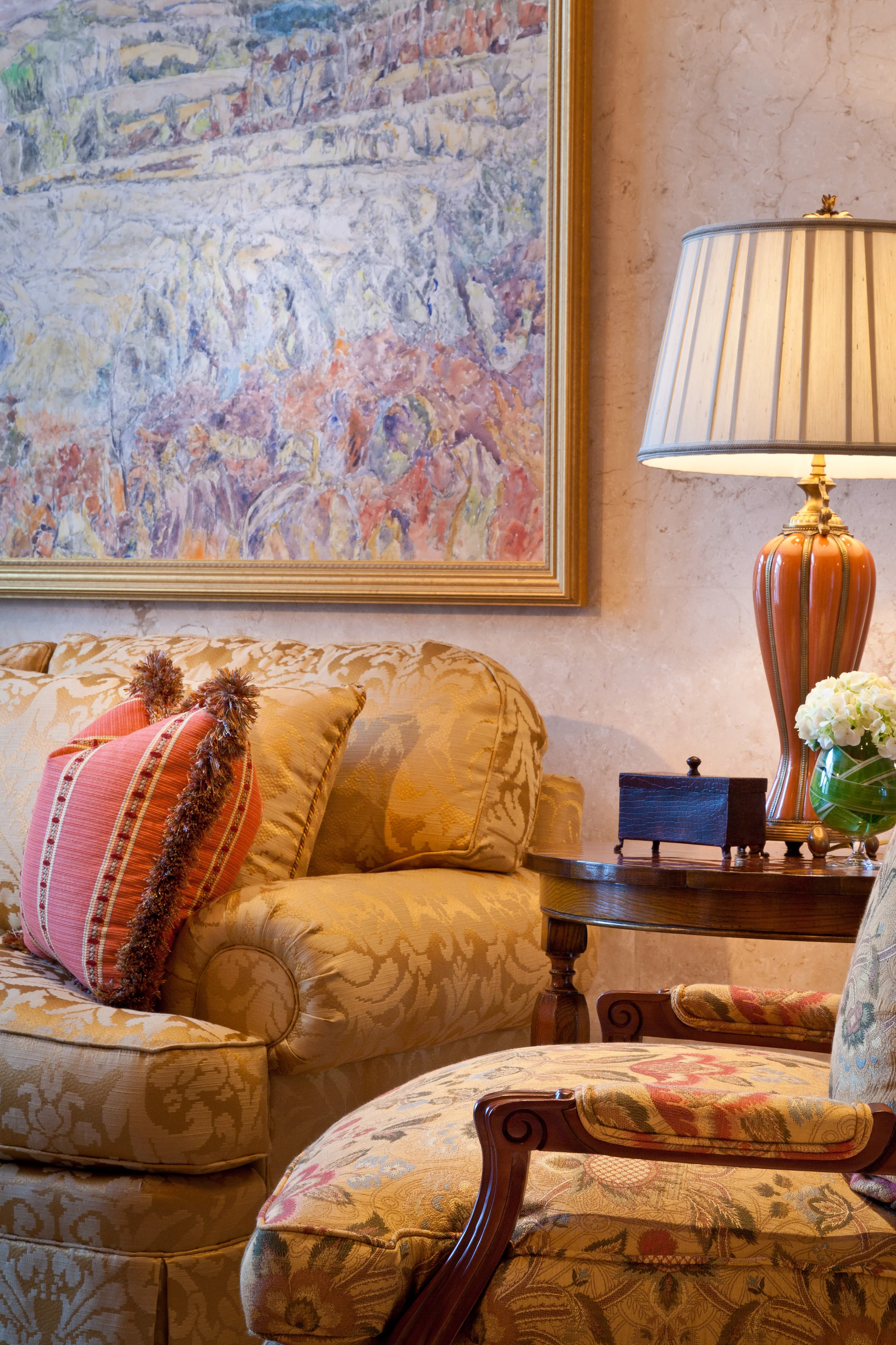 Smooth textures and delicate patterns work well against the richly veined stone wall panelling that wrap this charming living room, which features “The River in Autumn” by noted Canadian artist Dorothy Knowles.